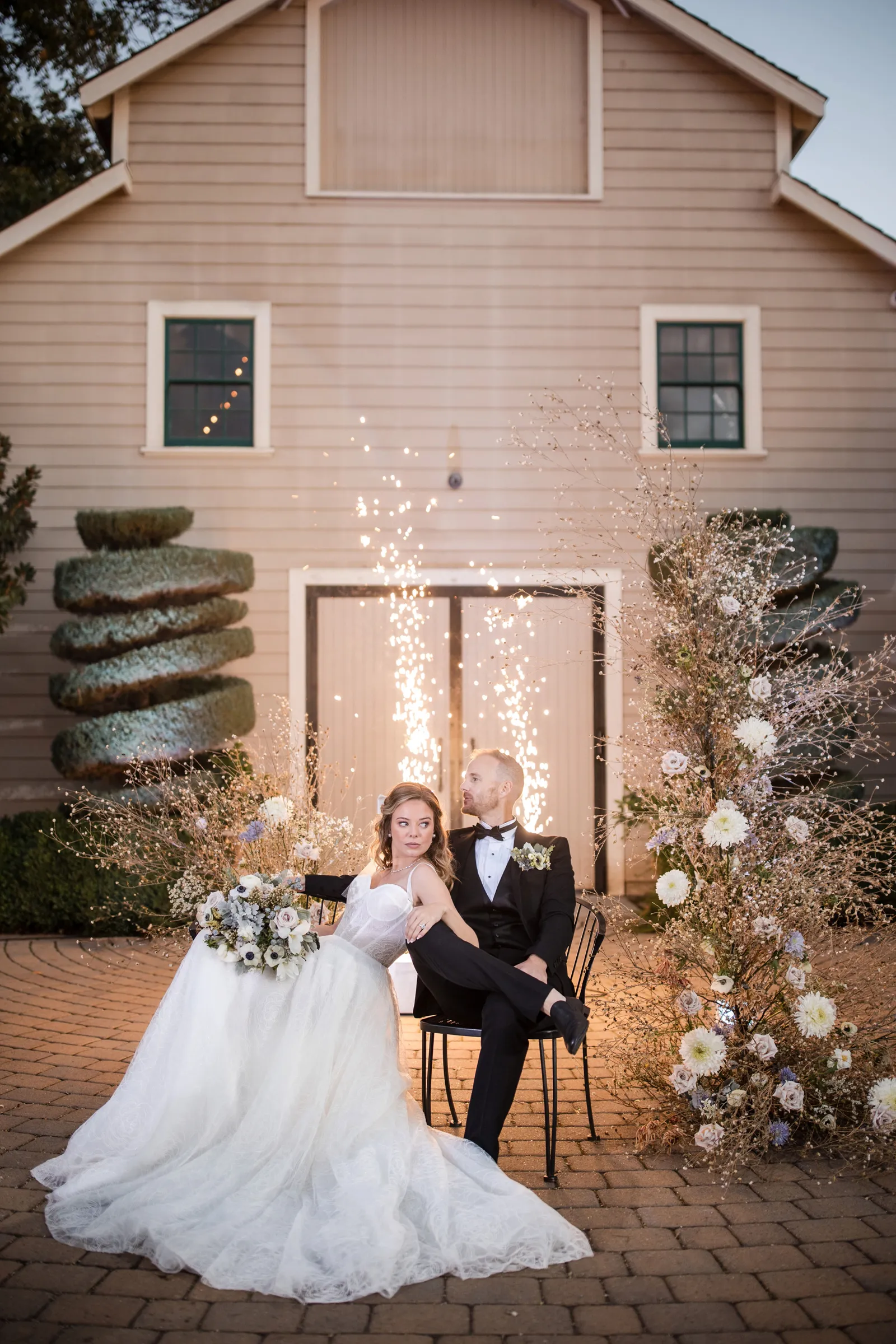 Bride and groom sitting together at Scribner Bend Vineyards with sparklers going off behind them.