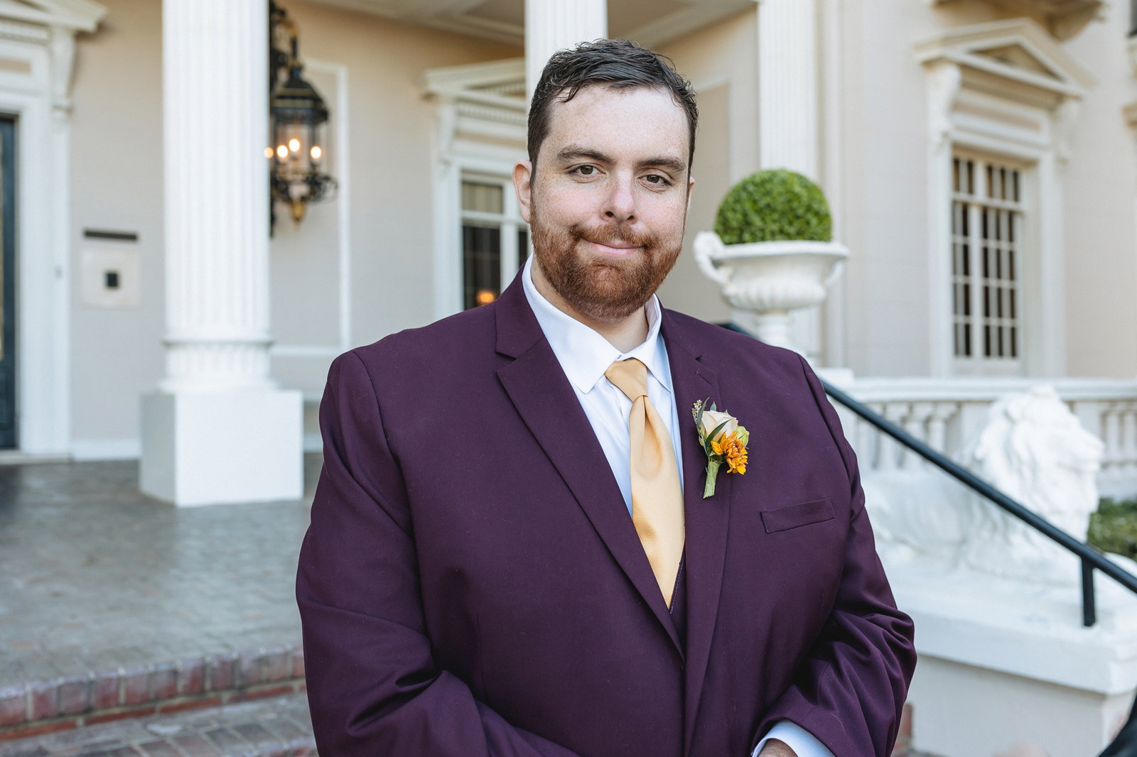 Groom posing at his mansion pretty outdoor wedding venue.